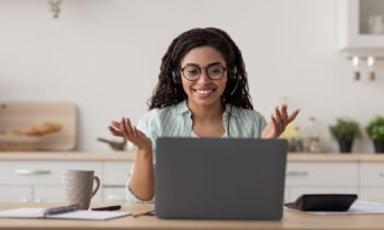 Online teacher working from home, using a laptop and headphones for a video call.