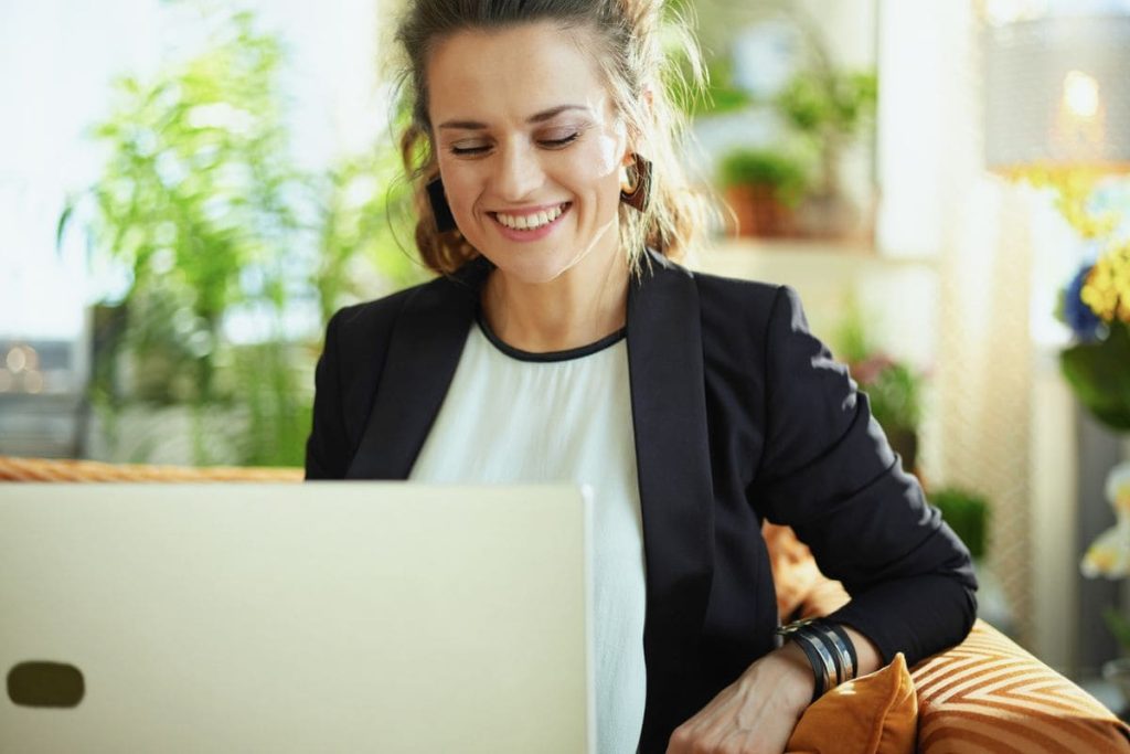 A woman using a laptop at home to search for remote jobs on a staffing agency website.