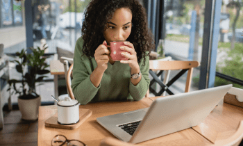 Woman working on her laptop a coffee shop drinking coffee