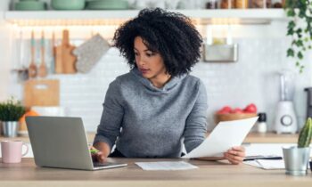 A woman working from home on a laptop in her kitchen.