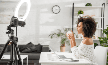 Woman sitting at desk with laptop filming a makeup tutorial for Instagram