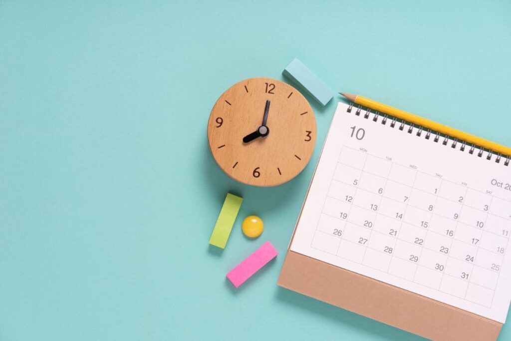 A woman's home office desk, with a calendar and clock.