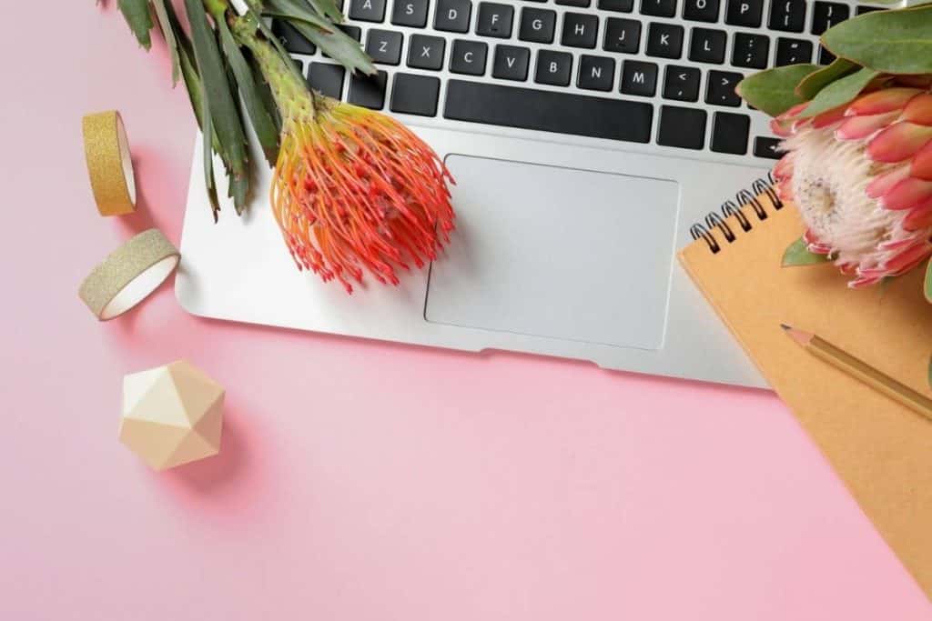 Still life of a home office desk with laptop, flowers, and office supplies