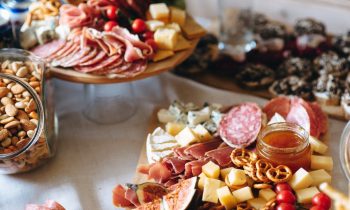 Various meats, cheeses, and fruits arranged on a charcuterie board,