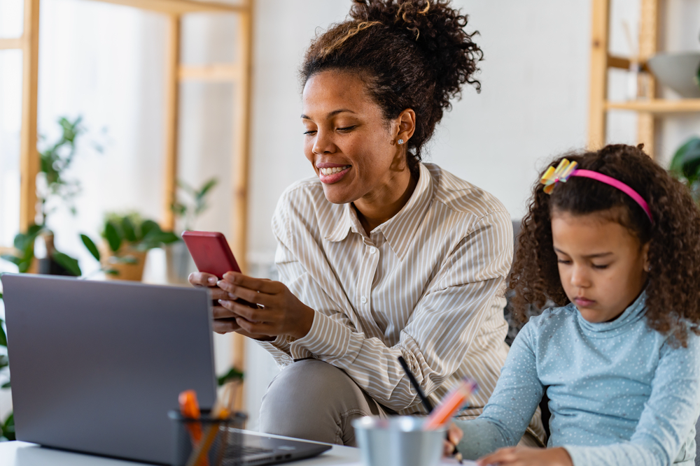 Mother working her stay-at-home mom job sitting next to her daughter