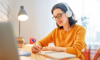 Woman working at home and writing in a notebook at a desk.