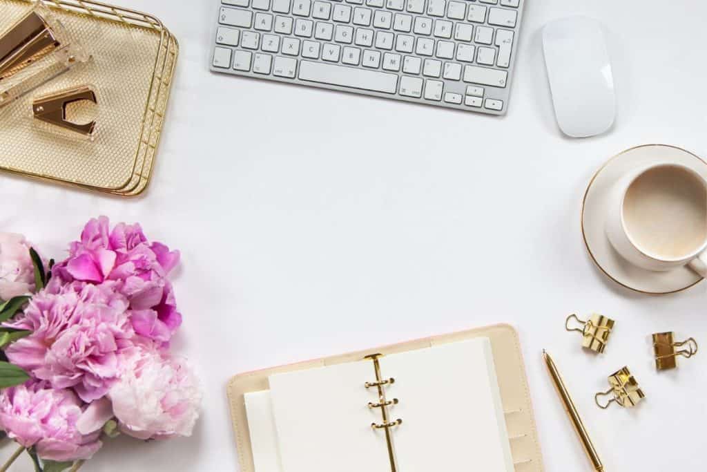 A woman's home office workspace with a keyboard, notebook, and flowers.