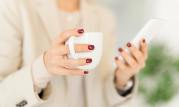 woman with painted finger nails drinking coffee using smartphone apps to make money