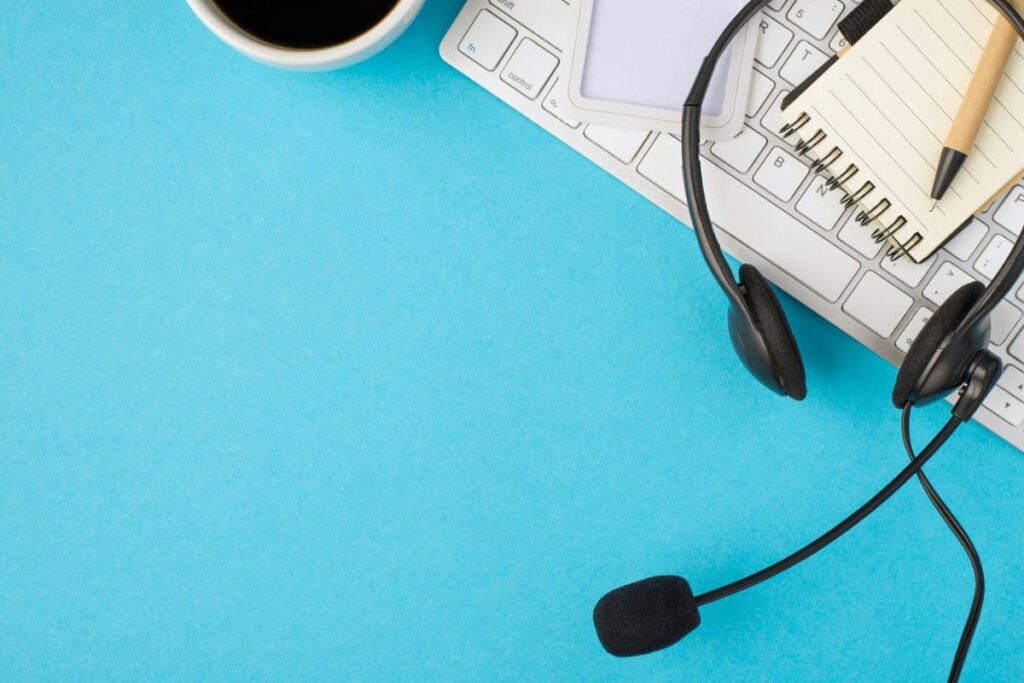 A work at home appointment setter's desk, with a keyboard, headset, and coffee.