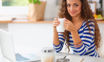 Young woman drinking coffee working on her laptop for her remote internet research job