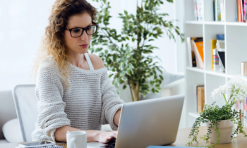 Young woman with glassed working on her laptop at home for her online editing job