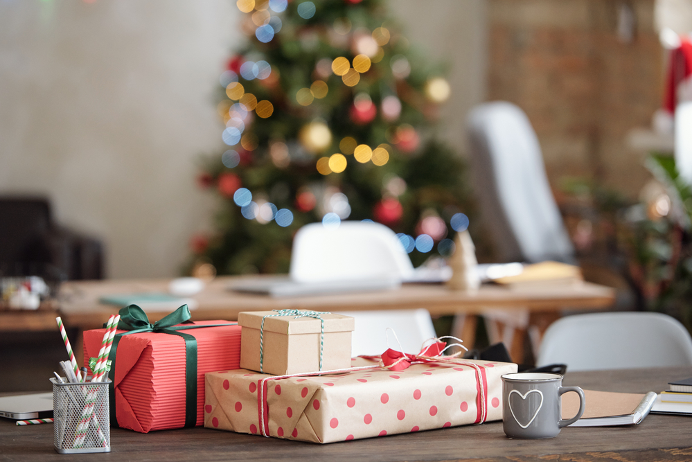 picture of wrapped gifts on desk in front of christmas tree