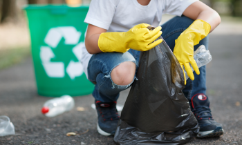 woman picking up trash in a parking lot for her litter pick up business